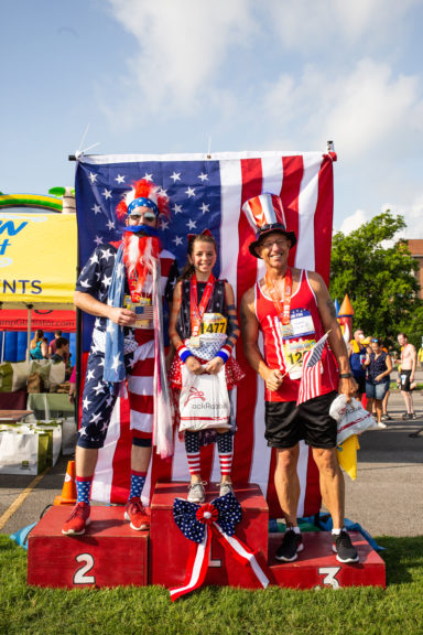 Run Nash 4th of July runners standing in front of U.S. Flag